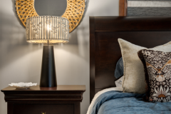 Bedside detail of a cozy bedroom with a dark wood nightstand and a modern lamp.