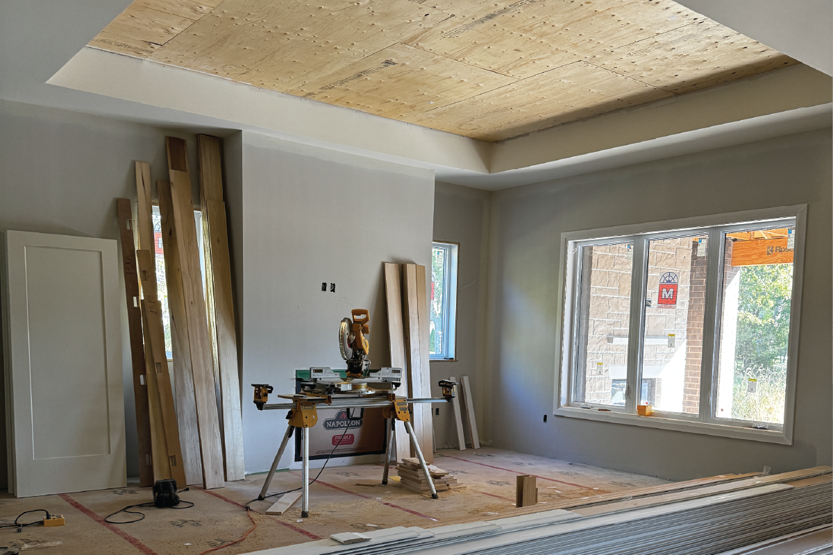 Forest Trail model home living room under construction with framed windows, plywood ceiling, and unfinished walls.
