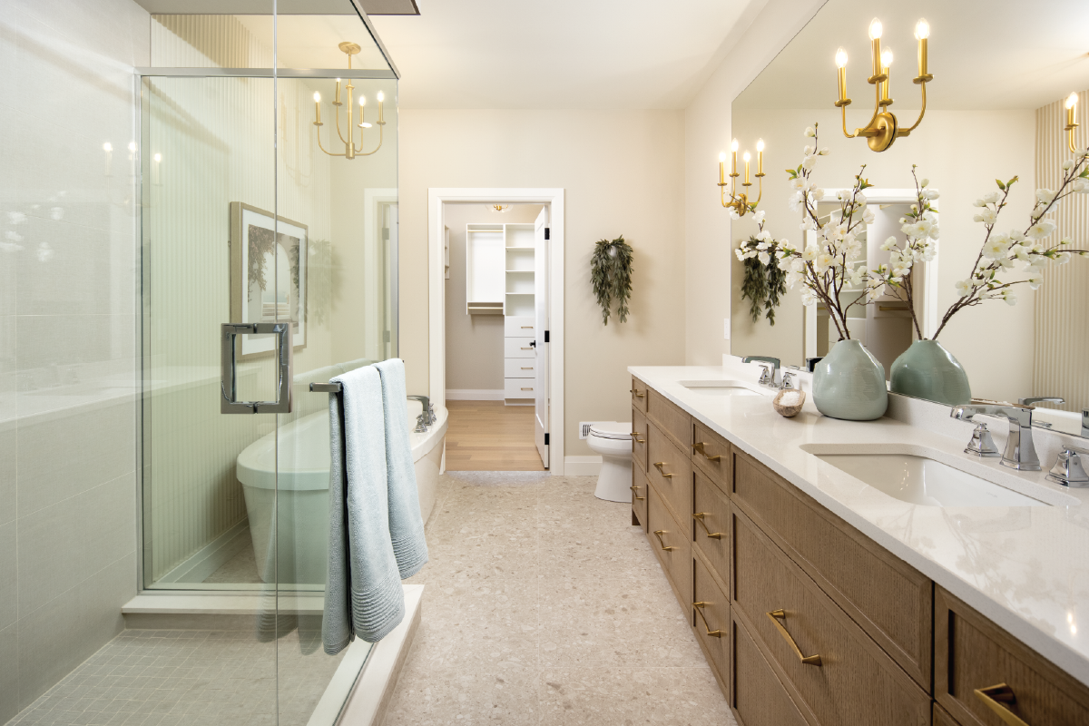 Forest Trail master ensuite bathroom featuring a glass walk-in shower, double vanity with gold hardware, and organic styling touches.