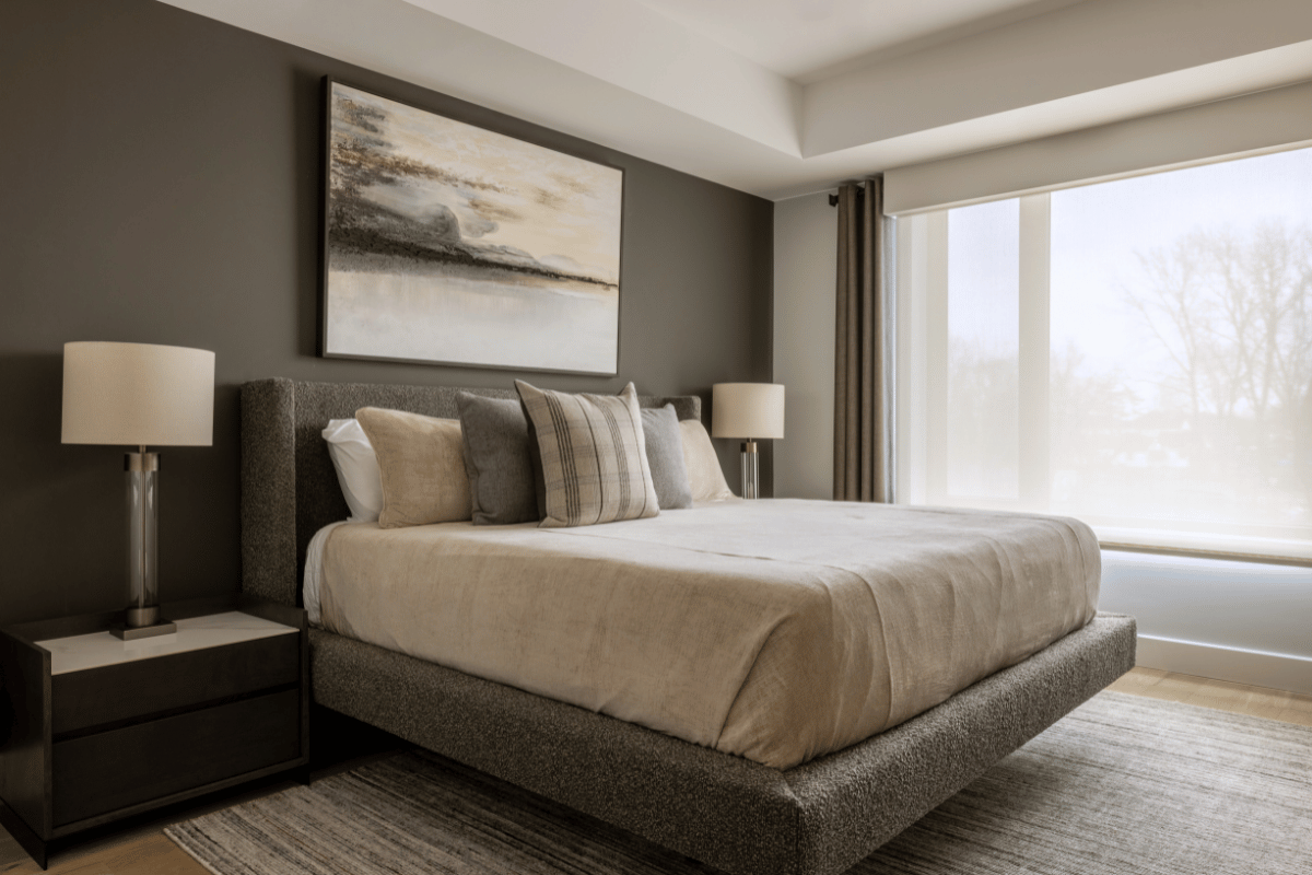 Styled bedroom featuring a minimalist queen bed, layered pillows, modern nightstands, and a serene landscape artwork at the Harbour Club Condo designed by Urbanhome Interior Design.