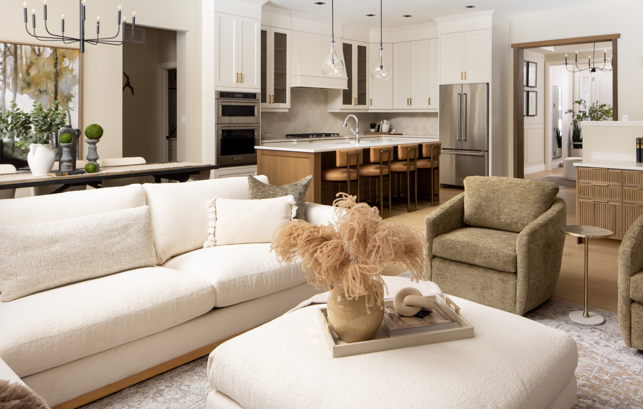 Modern open-concept living room and kitchen with neutral tones, white cabinetry, and wood accents.